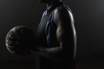 Fotobehang Zoom on a side of  a basketball player holding a basketball © WavebreakMediaMicro