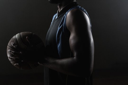 Zoom on a side of  a basketball player holding a basketball