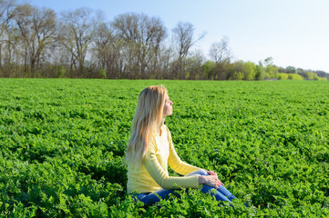Young woman resting on the green grass in the meadow