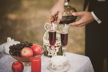 Close up of man hands holding bottle of red wine. Anonymous person pouring drinks in glasses. Man smartly dressed in black suit and white shirt. Preparation for romantic dinner.