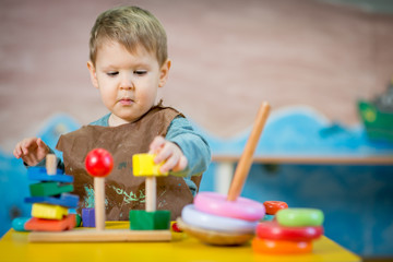 Fototapeta na wymiar Little caucasian boy playing with Montessori toy in pre-school