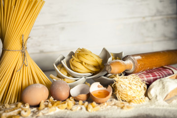 Small bowls with different pasta on floured surface