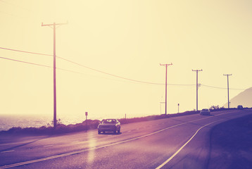 Fototapeta na wymiar Vintage toned ocean road against sun with flare effect, travel concept.