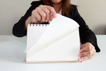 Businesswoman hand turning page of notebook.