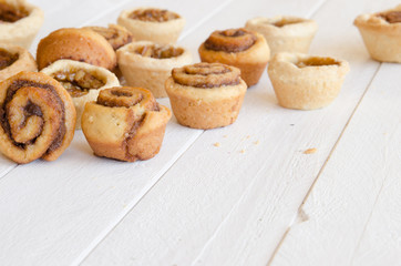 Freshly baked butter tarts and cinnamon rolls on a rustic, white