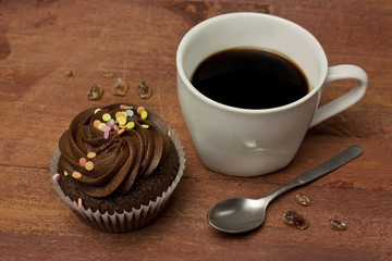 Black coffee, chocolate cupcake, small spoon, cane sugar