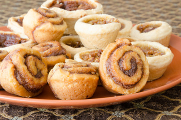 An orange plate with tasty baking treats on a brocade tablecloth