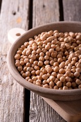 Clay bowl with dried chickpeas on wooden board