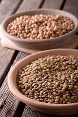 Clay bowls with lentils and chickpeas on wooden board