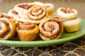 A green plate with tasty baking treats on a brocade tablecloth