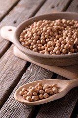 Chickpeas on wooden spoon and in clay bowl