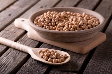 Wooden spoon in front of clay bowl both full of chickpeas