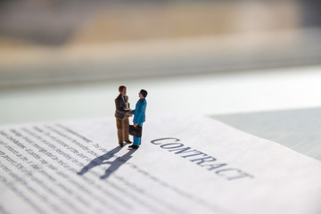 selective focus of miniature employees handshaking. Image of business contract. - obrazy, fototapety, plakaty