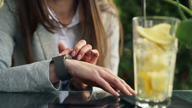 Woman hand using smartwatch sitting in cafe in city
