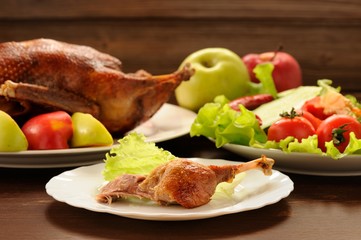 Roasted duck served with fresh vegetables and apples on wooden