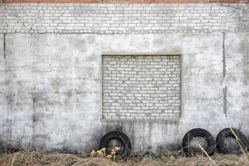 Fototapeta premium White brick and concrete wall exterior texture outside with tires next to it.