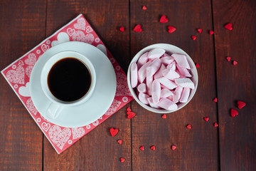 A jar of colored marshmallows on wooden background and cup of co