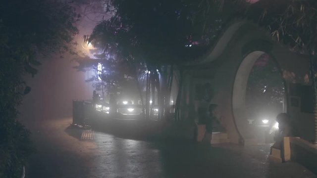 View of traditional chinese round shaped  arch or gates and trees at night in fog. Handheld wide shot. Mysterious atmosphere. Rainy weather in Hong Kong at night. Very high humidity.