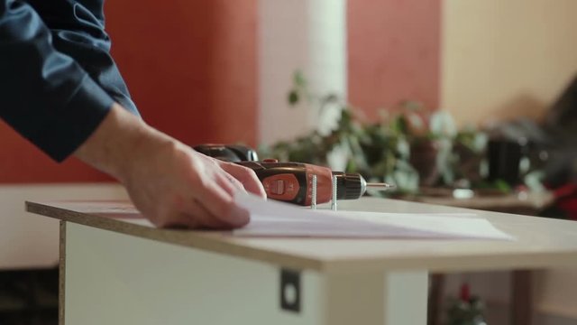man assembles furniture using a power screwdriver