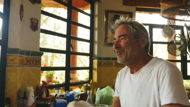 An attractive baby boomer man is having fun throwing pizza dough in the air