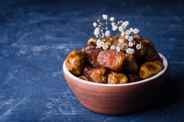 Fresh dates in clay bowl on stone background. Selective focus