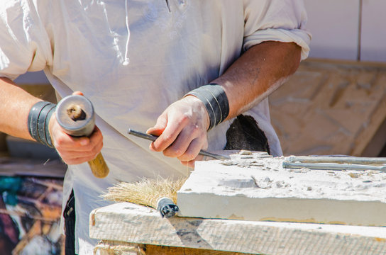 Unrecognizable man working with chisel on stone