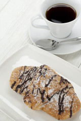 chocolate croissants on plate with cup of coffee