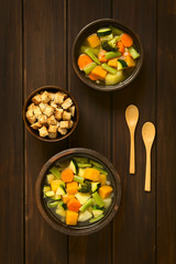 Frische Gemüsesuppe aus Zucchini, grüne Bohnen, Karotten, Brokkoli, Kartoffeln und Kürbis in rustikale Schüsseln, mit Croutons an der Seite, fotografiert mit natürlichem Licht