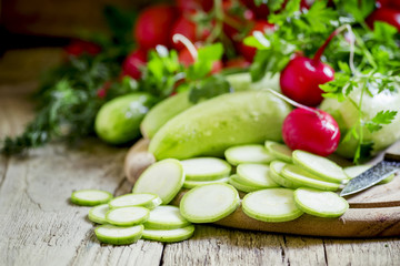 Round zucchini slices and fresh radish, vintage wooden backgroun