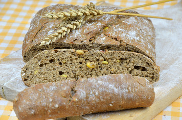 Sliced dark rustic bread and wheat ears on top
