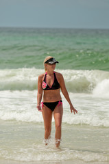 Mom in bikini swimsuit walking in ocean at the beach.