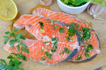 Salmon steaks prepared for baking. Spiced with salt, lemon, parsley, oil, garlic...