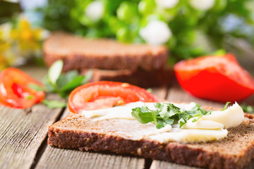 Sandwich from rye bread with oil, greens and tomatoes
