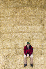 Naklejka na ściany i meble smiling man sitting on bale of hay