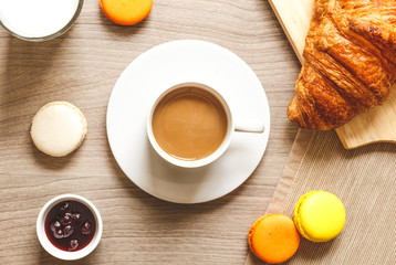 sweet breakfast with coffee, macaroons and croissants on wooden table