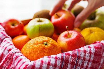 Box full of fresh fruits. Woman chooses fruits. Fruit harvest - apples, oranges, lemon, kiwi, banana. Rustic background.
