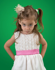 Cute little girl with white dress and a serious look in her eyes on a green background