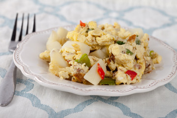 Scrambled eggs with Anaheim chilies, boiled potatoes, green peppers, and onions on a blue and white place mat