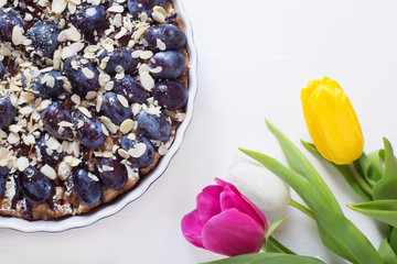  pie with plums  on a white wooden background, tulips