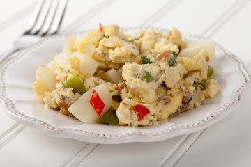 Scrambled eggs with Anaheim chilies, boiled potatoes, green peppers, and onions side view on white wood