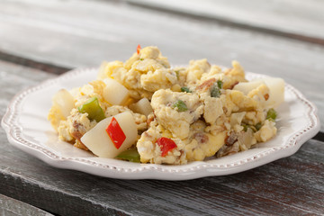 Scrambled eggs with Anaheim chilies, boiled potatoes, green peppers, and onions macro shot on a weathered barn wood table