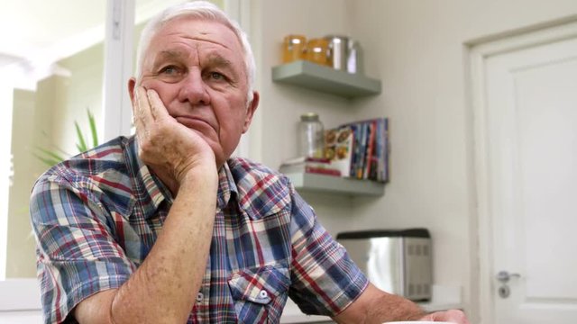 Sad old man thinking in kitchen