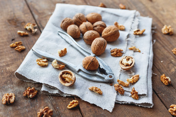 Glass bowl with walnuts on rustic homespun napkin. Healthy snack on old wooden background.