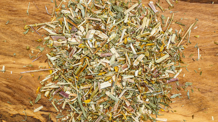 Heap of dried herb leaves on wooden surface