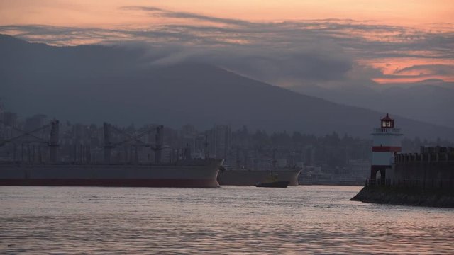 Freighter in Burrard Inlet Dawn. 4K UHD. Brockton Point in Vancouver at the east end of Stanley Park on Burrard Inlet. A freighter arriving at dawn. British Columbia, Canada. 4K. UHD.
