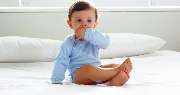Cute baby with nightwear sitting on a bed