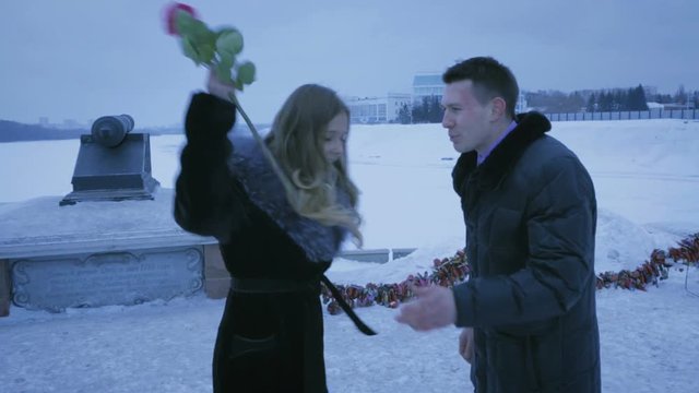 If late, a man gives rose to girl. She angrily throws it.