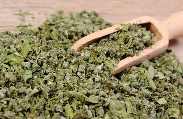 Dried marjoram with spoon on wooden background