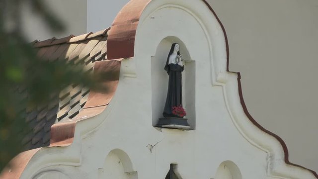 Tilt shot to the the statue of a catholic nun on the frontispiece of a church