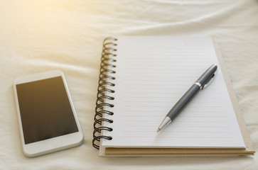 pen on open blank notebook and mobilephone